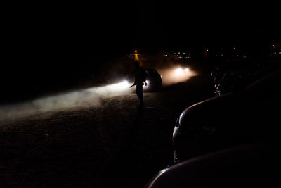 Rear view of silhouette man on illuminated street at night