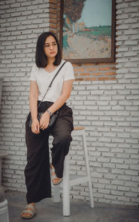 Portrait of young woman standing against wall