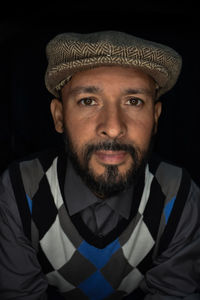 Portrait of man wearing hat against black background