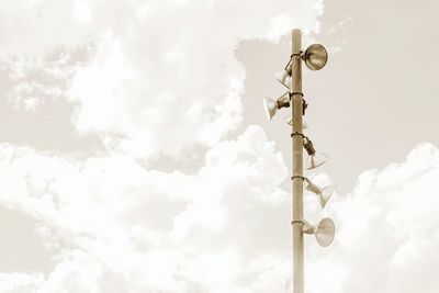 Low angle view of lighting equipment on pole against cloudy sky