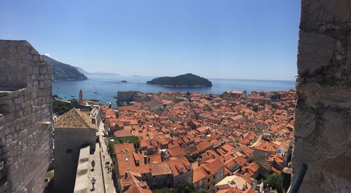 High angle view of townscape by sea against blue sky