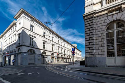 Road by buildings against sky in city