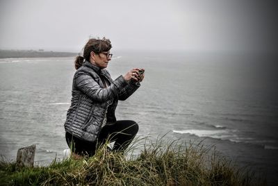 Rear view of woman photographing on beach