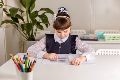 A girl pupul sits at a desk in the classroom and reads a book. back to school concept