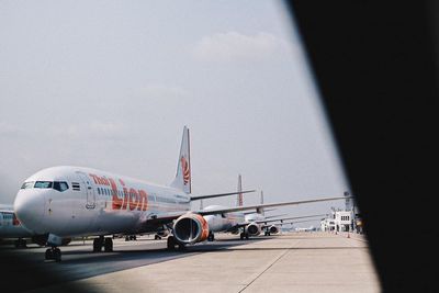 Airplane on airport runway against sky