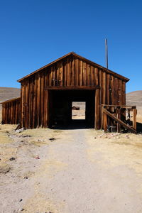 Abandoned house in desert against clear blue sky