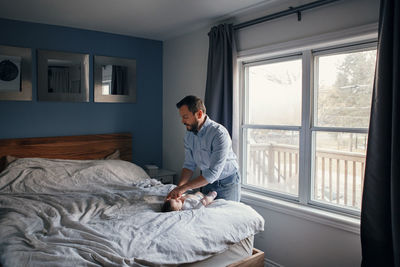 Full length of man sitting on bed at home