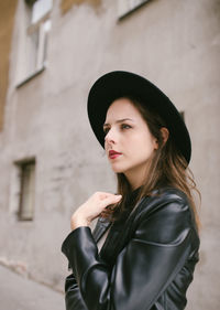 Profile portrait of young woman wearing black hat and leather jacket