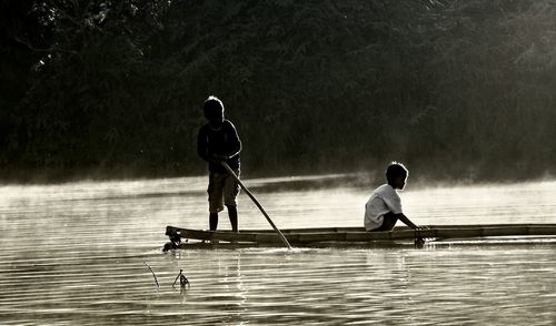 Boys rowing boat in lake