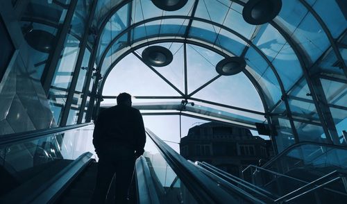 Rear view of silhouette man on escalators in building