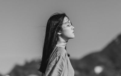 Side view portrait of a girl looking away against sky