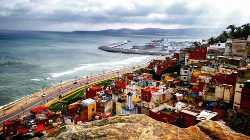 Aerial view of sea by townscape against storm cloud