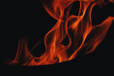 Close-up of burning candle against black background