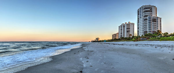 Sea and buildings against sky during sunset