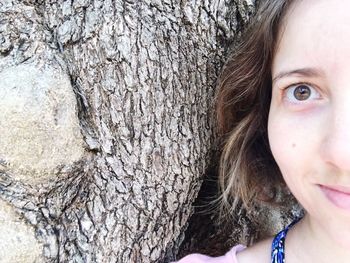 Close-up portrait of girl with tree trunk