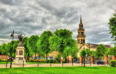 Trees in front of historical building against cloudy sky