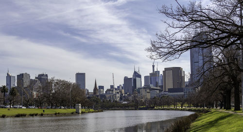 City by river and buildings against sky