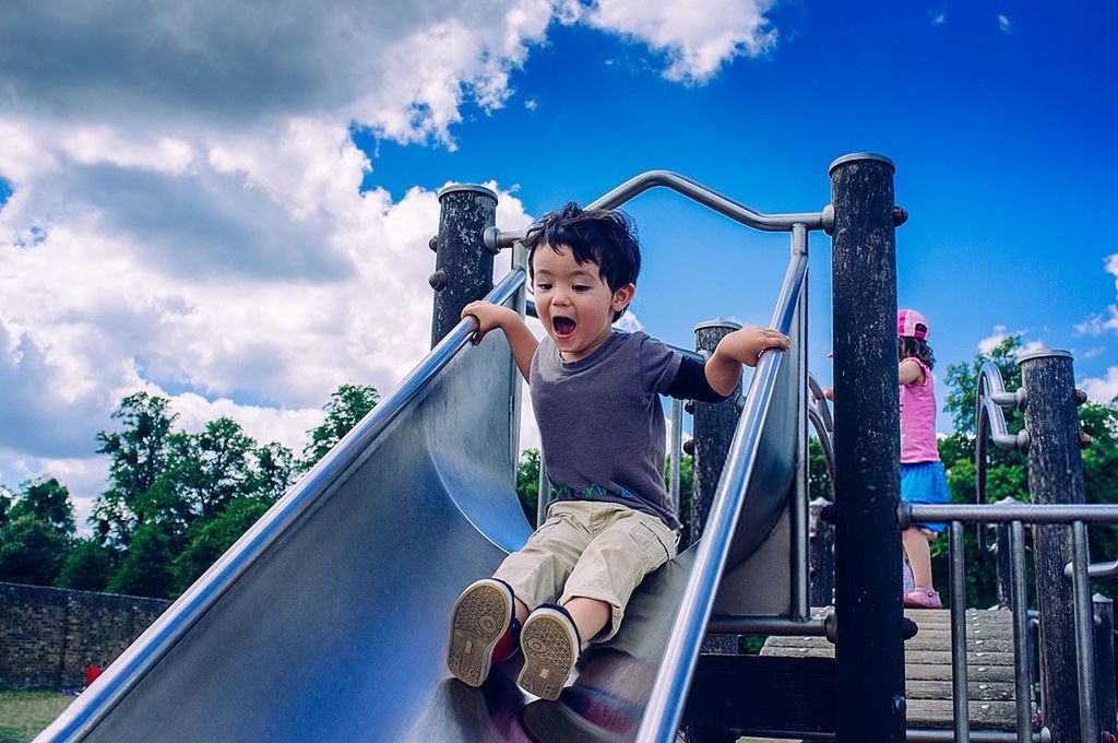 LOW ANGLE VIEW OF BOY PLAYING ON SLIDE