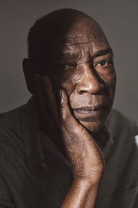 Portrait of senior man with hand on chin in studio