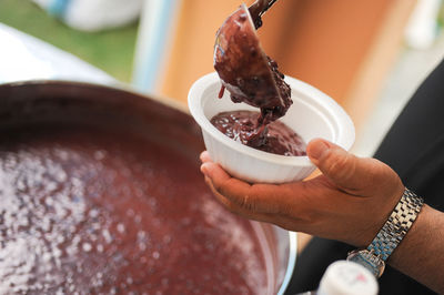 Cropped hand of man pouring cooked food in bowl