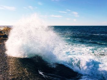 Waves splashing on sea against sky