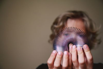 Boy holding coiled spring toy against wall at home