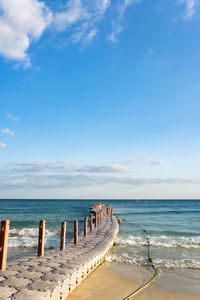 Wooden posts on beach against sky