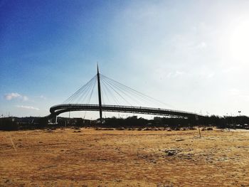 Suspension bridge over field against sky