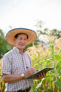 Portrait of woman wearing hat standing against plants