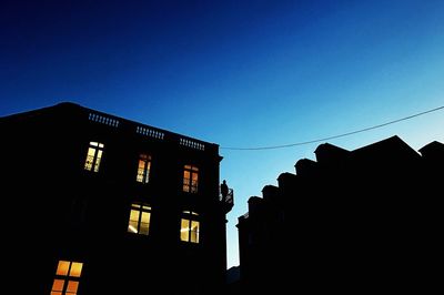 Low angle view of silhouette built structure against clear blue sky