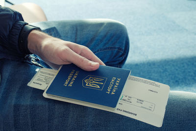 Midsection of passenger holding passport and ticket