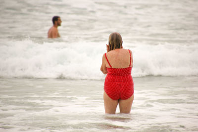 Rear view of woman standing at beach