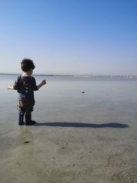 Boy on beach against sky