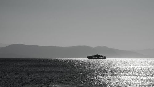 Silhouette boat sailing on sea against clear sky