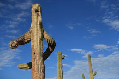 Low angle view of cross on wooden post against sky