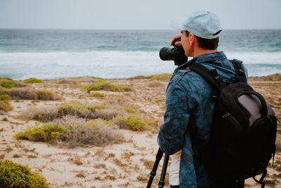 Rear view of man photographing at beach