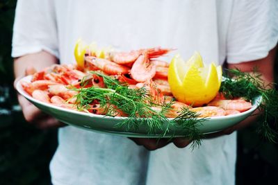 Midsection of man holding seafood in plate