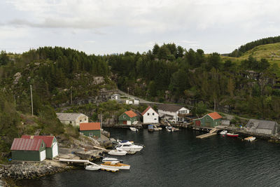 Houses and trees by lake against sky