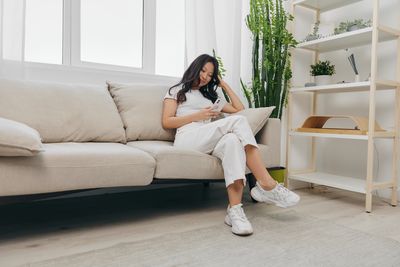 Portrait of young woman sitting on sofa at home