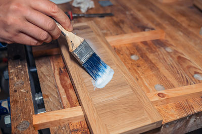 Varnishing a wooden drawer, carpentry workshop. varnish is applied to a wooden board with a brush