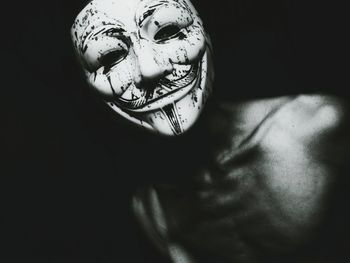 Close-up of man wearing mask against black background