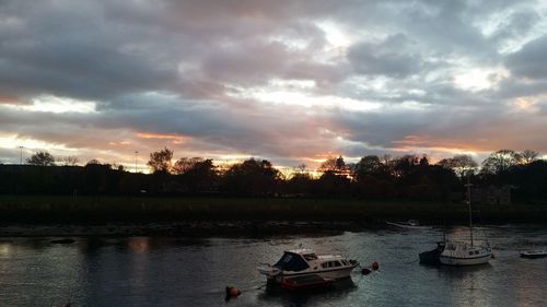 Boats in lake against sky during sunset