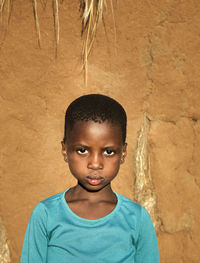 Portrait of boy standing against wall