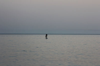 Silhouette person in sea against clear sky