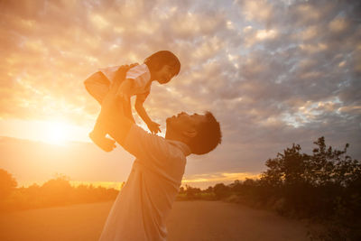 Father with son against sky during sunset