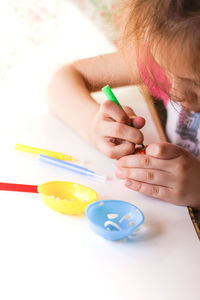 Close-up of girl painting easter egg on table