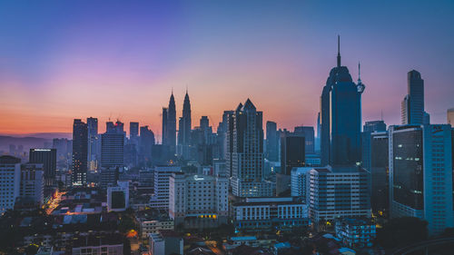 Modern buildings in city against sky during sunset