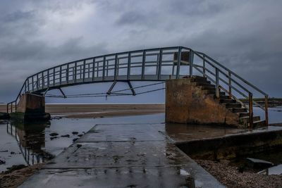 Abandoned bridge over sea against sky