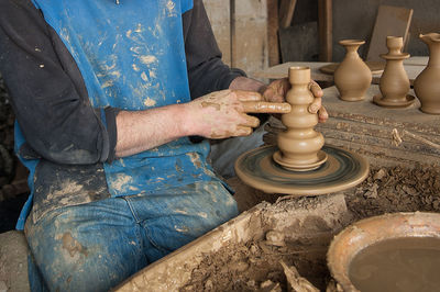 Midsection of potter molding a shape at workshop