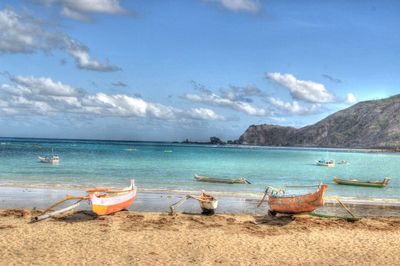 Boats moored at beach against sky